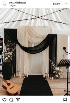 a black and white wedding ceremony setup with candles, flowers, and an acoustic guitar