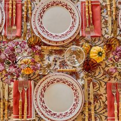 the table is set with plates, silverware and orange napkins for an elegant dinner