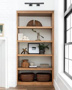 a white brick wall with shelves and baskets on the bottom shelf in front of it