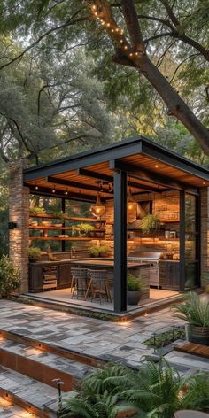 an outdoor kitchen and dining area is lit up by string lights on the trees in the background