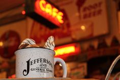 there is a coffee cup on the table in front of a store sign and neon signs