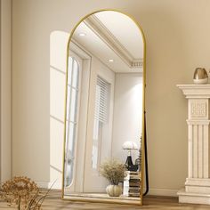 a large mirror sitting on top of a wooden floor next to a vase with flowers