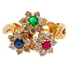 14k yellow gold ring. This beautiful yellow gold ring is a triple flower motif, set with a round faceted red ruby (approximately 0.12 CTS), a round faceted green emerald (approximately 0.10 CTS) and a round faceted blue sapphire (approximately 0.12 CTS), each surrounded by round brilliant cut diamonds, approximately 0.42 TCW, prong set. The ring is finished with swirled, twisted shoulders and a high polished shank. Marks: 14k Dimensions: 1/2" across the top x 1/2" wide Weight: 2.9 gross dwt Yellow Gold Flower-shaped Multi-stone Rings, Yellow Gold Flower-shaped Rings With Multi-stone, Yellow Gold Floral Multi-stone Rings, Formal Multi-stone Yellow Gold Flower Ring, Ruby Emerald, Flower Motif, Red Ruby, Yellow Gold Ring, Flower Ring