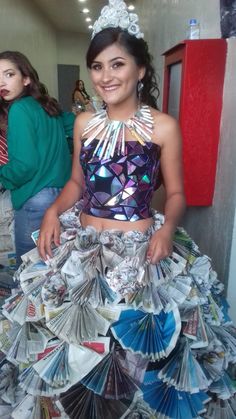 a woman in a dress made out of magazines and paper fans is smiling at the camera