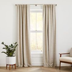 a living room with a chair, window and potted plant