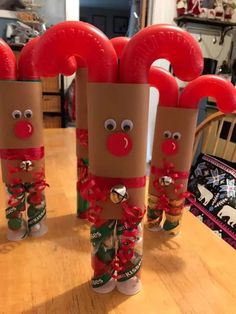 three toilet paper roll christmas decorations with noses and bells on them sitting on a table