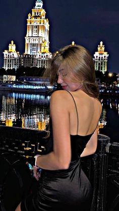 a woman in a black dress looking at the city