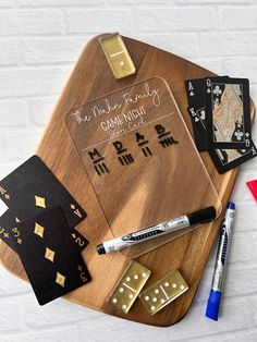 a wooden board with dice, cards and pen on it next to some other items