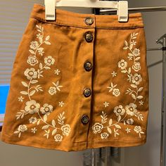 Camel Brown With White Flower Embroidery On The Side. Chunky Buttons Lining The Front. Material Is Like A Corduroy/Denim. Never Worn. Size Small, Runs About A Size 1/2. Spring Embroidered Beige Skirt, Casual Embroidered Fall Skirt, Casual Mini Skirt With Embroidered Hem, Fairy Academia, White Flower Embroidery, Skirt Embroidery, Embroidery Skirt, Brown Flower, Faux Leather Mini Skirt