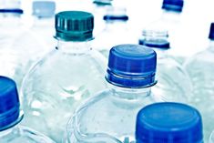 there are many water bottles lined up in the row, one is empty and the other has blue caps