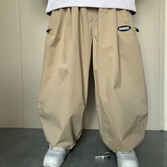 a person standing in front of a white wall with his feet on the ground wearing beige pants