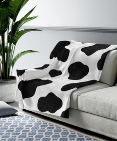 a living room with a cow print blanket on the couch and potted plant next to it