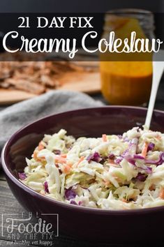 a purple bowl filled with coleslaw next to a jar of mustard and carrots