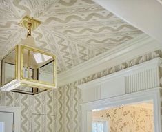 a light hanging from the ceiling in a room with white walls and patterned wallpaper