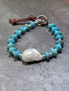 "Exquisite 10mm AAA Kingman Turquoise paired with sterling silver beads and featuring 1 AAA Baroque Pearl. Finished with a handmade Hill Tribe Silver button and leather loop to close at approximately 7\" and 8\". Will fit wrists 6.5\" - 7.5\". **Please note that due to the one of a kind nature of these large Baroque Pearls, each bracelet may differ slightly in composition but will contain the exact same materials as shown. Your turquoise beauty will arrive in my signature logo box, ready for gif Bohemian Turquoise Pearl Bracelet With Round Beads, Handmade Turquoise Pearl Bracelet With Round Beads, Handmade Adjustable Turquoise Pearl Bracelet, Hill Tribe Silver, Silver Button, Kingman Turquoise, Silver Buttons, Belfast, Baroque Pearls