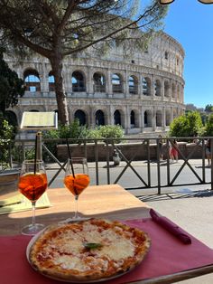 two glasses of wine and a pizza on a table in front of the colossion