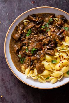 a bowl filled with pasta and meat covered in gravy on top of a table