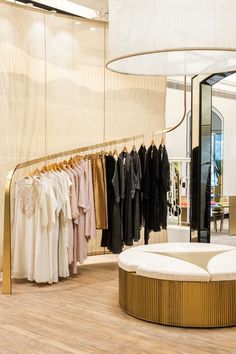 a clothing store with clothes on hangers and a circular bench in front of it