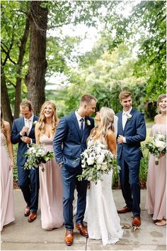 a group of people standing next to each other in front of trees and bushes with flowers