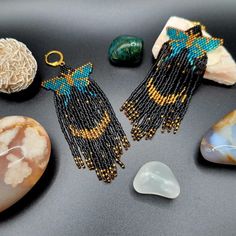 beaded earrings with beads and stones on a black table next to rocks, shells and other items