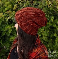 a woman with long hair wearing a red knitted hat and looking off into the distance