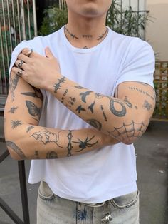 a man with tattoos on his arm and arms is standing in front of a fence