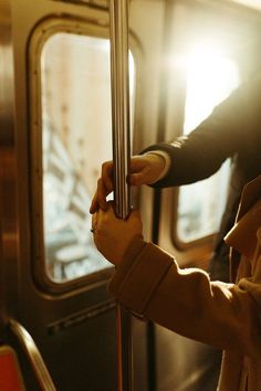 a person holding onto the handle of a subway train door with sunlight streaming through it