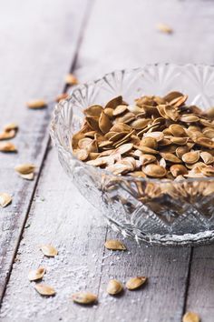 a glass bowl filled with seeds on top of a wooden table