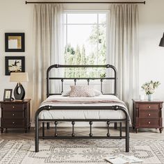 a bedroom with a metal bed frame and two nightstands in front of the window