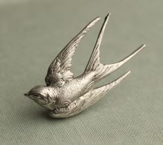 a silver bird brooch sitting on top of a table