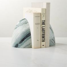 two books are stacked on top of each other in front of a marble bookend