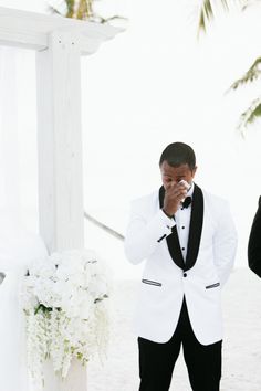 a man in a tuxedo is wiping his nose