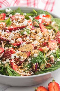 a salad with strawberries and feta cheese in a white bowl on a table