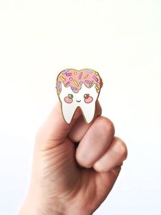 a person holding up a pink and white pin with donuts on it's face