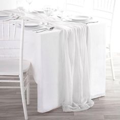 the table is set with white linens and place settings for two people to sit at