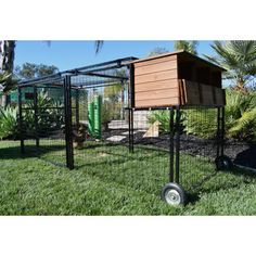 an outdoor chicken coop with two chickens in it and one on top of the cage