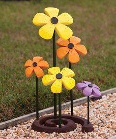 three fake flowers are sitting in the gravel