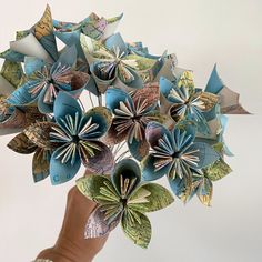 a person's hand holding a bunch of origami flowers in blue and green