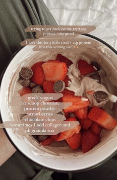 a bowl filled with strawberries on top of a white table next to a person's legs