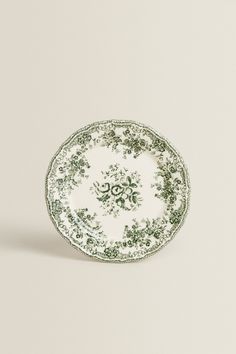 a green and white plate with an ornate design on the rim, set against a plain background