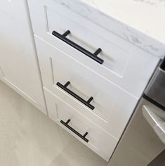 an image of a kitchen setting with white cupboards and black handles on the drawers