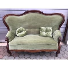 a green couch sitting on top of a brick floor next to a wall and door