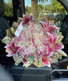 a bouquet of pink and white flowers in the back seat of a car