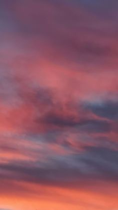 an airplane is flying in the sky at sunset or dawn with pink and blue clouds