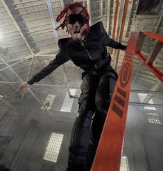 a man with dreadlocks on his head is walking down a ramp in a warehouse