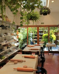 a restaurant with plants hanging from the ceiling and long tables in front of them on shelves