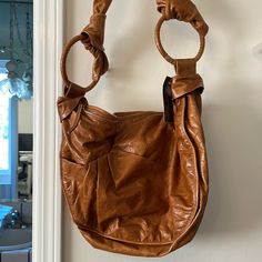 a brown purse hanging on the wall with a ring around it's neck and handles