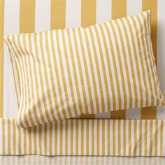 two yellow and white striped pillows sitting on top of a bed next to each other