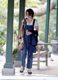 a woman in overalls is walking down the street