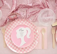 a pink and white plate with a woman's face on it next to utensils